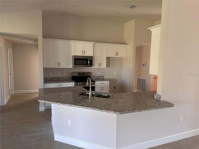 kitchen featuring appliances with stainless steel finishes, white cabinets, a sink, and a peninsula