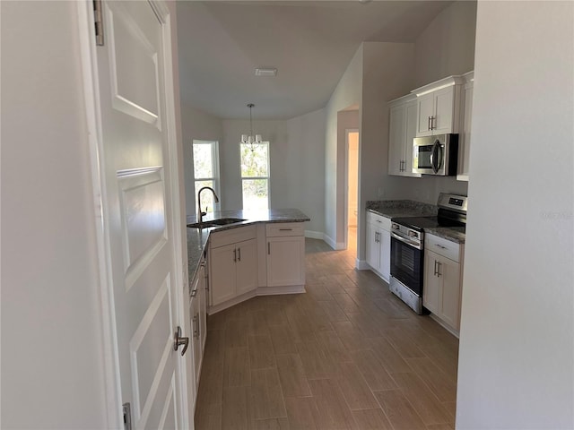 kitchen with stainless steel appliances, white cabinetry, a sink, and decorative light fixtures