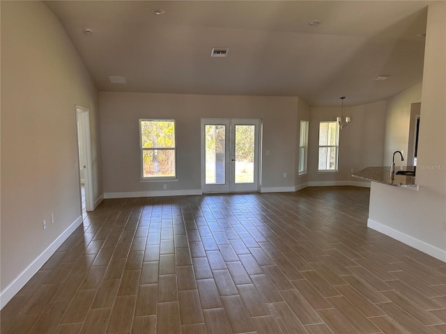 unfurnished living room featuring baseboards, wood tiled floor, visible vents, and a sink