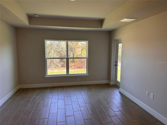 empty room with dark wood-style flooring, plenty of natural light, visible vents, and baseboards