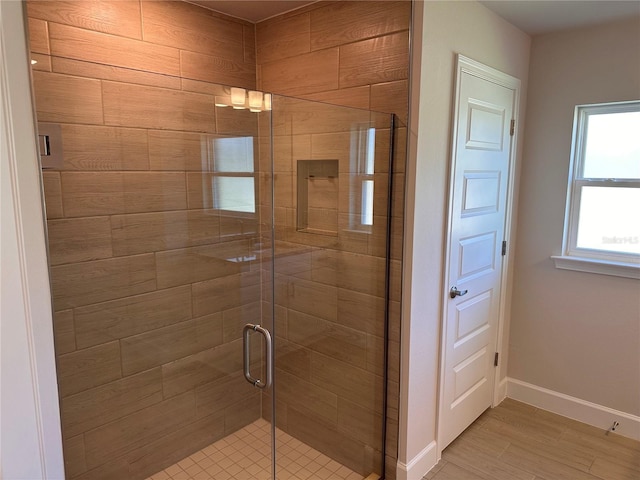 bathroom with a shower stall, baseboards, and wood finished floors