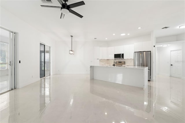 kitchen with ceiling fan, pendant lighting, a center island with sink, white cabinetry, and stainless steel appliances