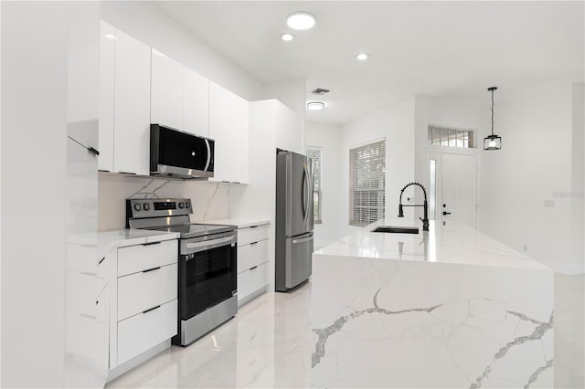 kitchen featuring light stone counters, pendant lighting, white cabinets, sink, and appliances with stainless steel finishes