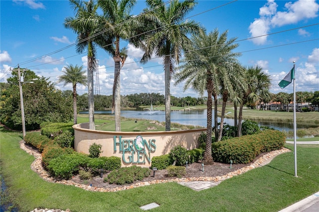 community / neighborhood sign with a water view and a lawn