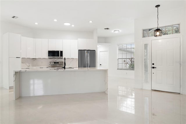 kitchen featuring appliances with stainless steel finishes, a wealth of natural light, hanging light fixtures, and white cabinets