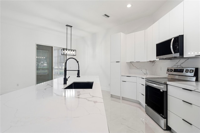 kitchen with light stone counters, stainless steel appliances, sink, white cabinetry, and decorative light fixtures