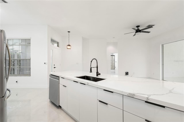 kitchen featuring sink, light stone countertops, hanging light fixtures, white cabinets, and appliances with stainless steel finishes