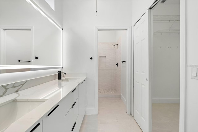 bathroom featuring tile patterned flooring, a tile shower, and vanity