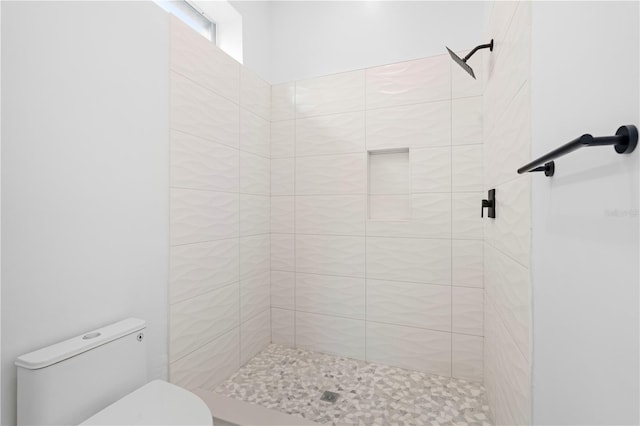 bathroom featuring tiled shower and toilet