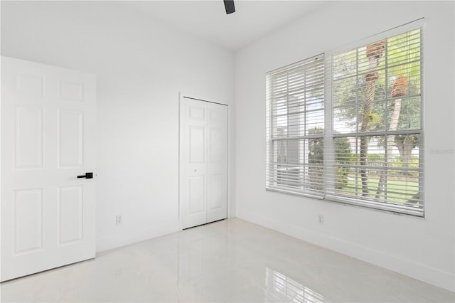 unfurnished bedroom featuring multiple windows, ceiling fan, and a closet