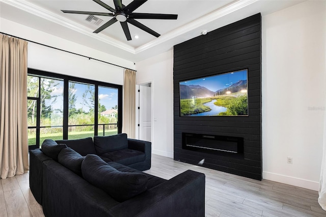 living room featuring ceiling fan, light hardwood / wood-style floors, a fireplace, and crown molding