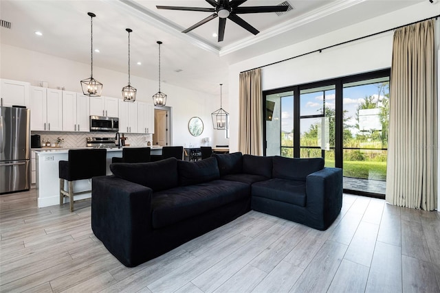 living room featuring ceiling fan, light wood-type flooring, and crown molding