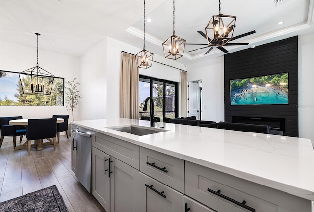 kitchen with a raised ceiling, hanging light fixtures, a fireplace, and sink