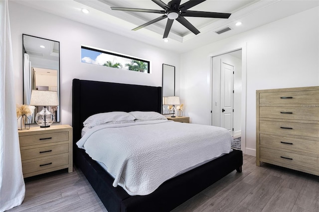 bedroom with ceiling fan, a tray ceiling, and dark wood-type flooring