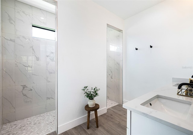 bathroom with tiled shower, vanity, and hardwood / wood-style floors