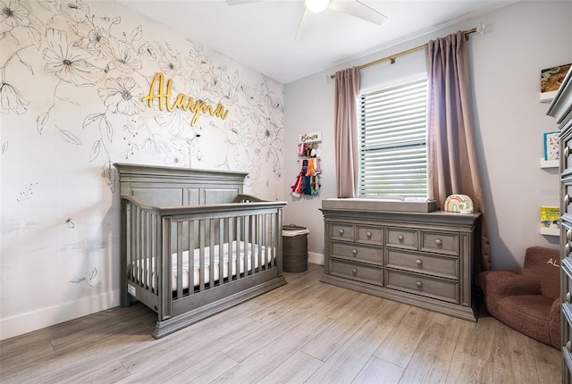 bedroom with light hardwood / wood-style floors, ceiling fan, and a nursery area