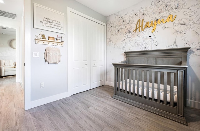 unfurnished bedroom featuring light wood-type flooring, a crib, and a closet