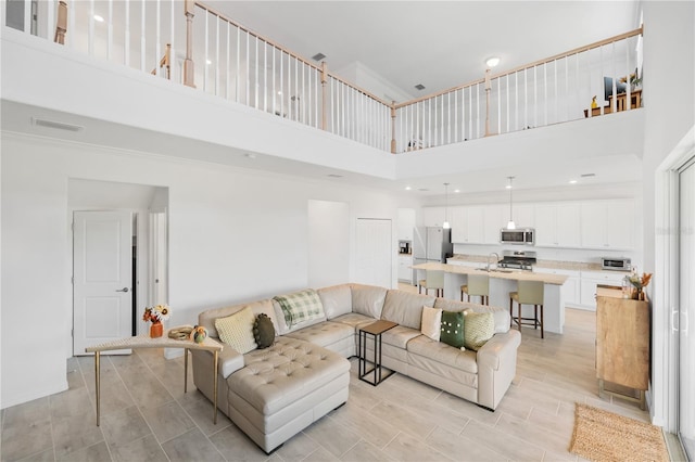 living room featuring sink, a towering ceiling, and light hardwood / wood-style flooring