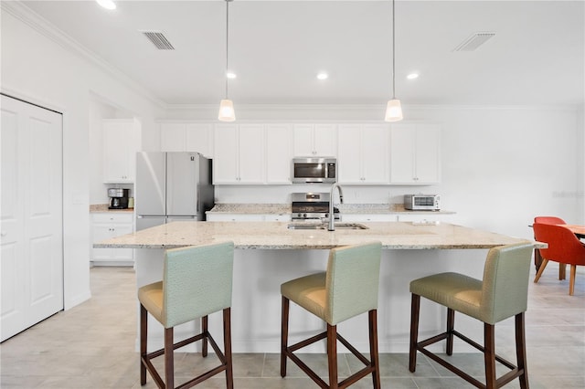 kitchen with white cabinetry, sink, hanging light fixtures, stainless steel appliances, and an island with sink