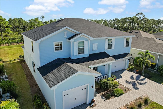 view of front of home with a front lawn, central AC unit, and a garage