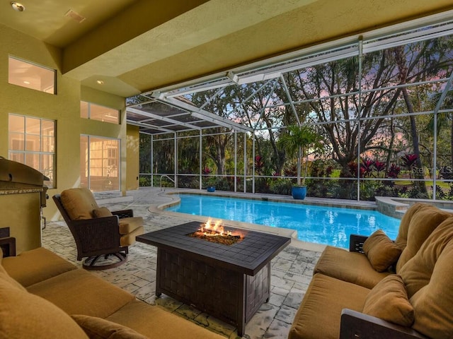 view of swimming pool with a lanai, a patio area, and an outdoor living space with a fire pit