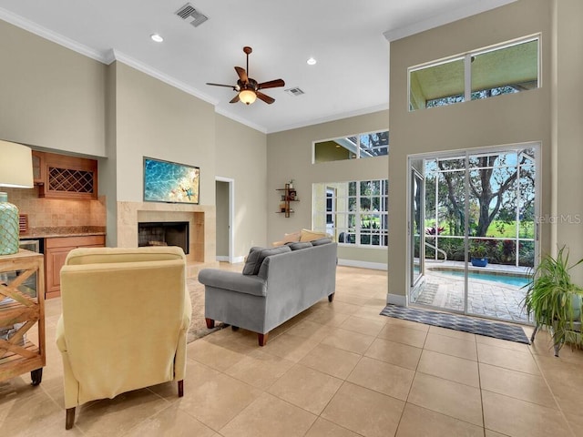 tiled living room with crown molding, a fireplace, a towering ceiling, and ceiling fan