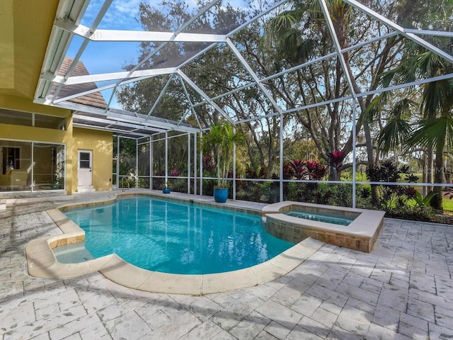 view of swimming pool featuring glass enclosure, an in ground hot tub, and a patio area