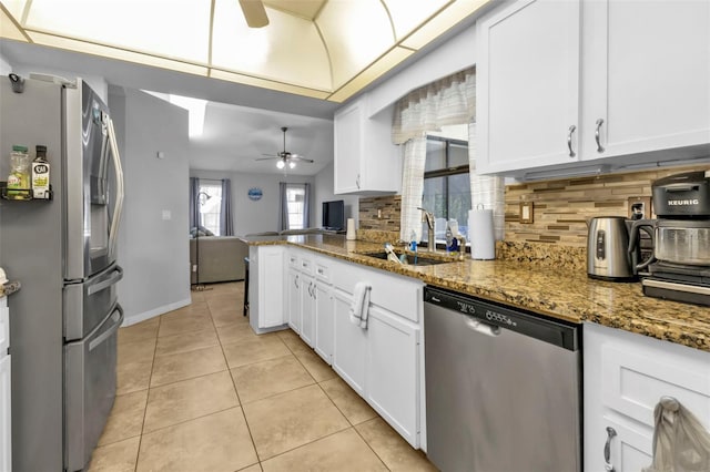 kitchen with dark stone countertops, white cabinetry, stainless steel appliances, and tasteful backsplash