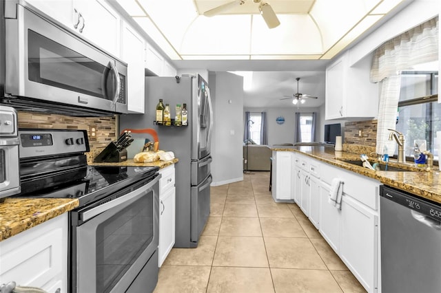 kitchen featuring appliances with stainless steel finishes, decorative backsplash, white cabinets, dark stone counters, and sink