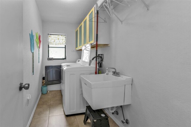 washroom with light tile patterned floors, washer and dryer, and sink