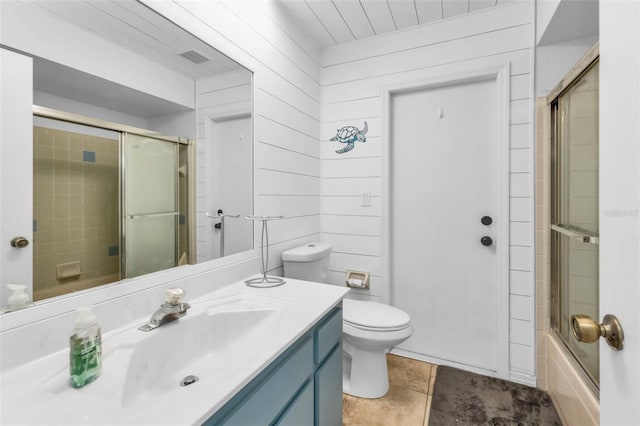 full bathroom with tile patterned flooring, combined bath / shower with glass door, wood walls, vanity, and toilet