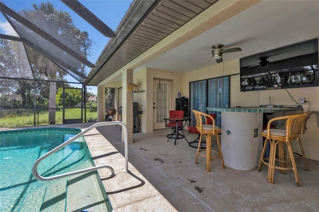 view of pool with ceiling fan, exterior bar, glass enclosure, and a patio