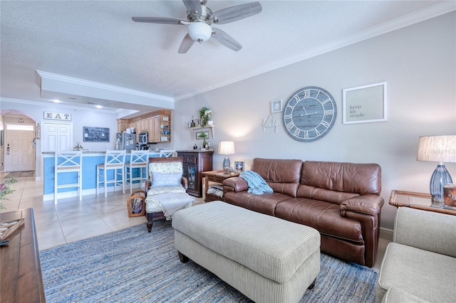 living room with crown molding, ceiling fan, tile patterned flooring, and a textured ceiling