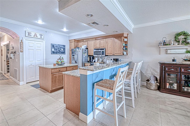 kitchen featuring light stone counters, stainless steel appliances, kitchen peninsula, ornamental molding, and a textured ceiling