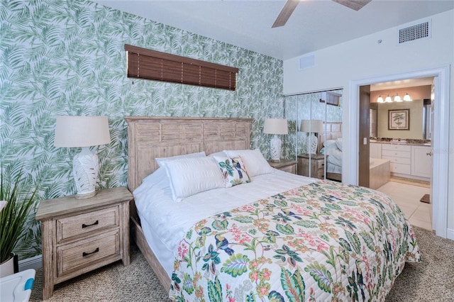 bedroom with light carpet, ceiling fan, and connected bathroom