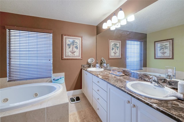 bathroom with tiled tub, tile patterned flooring, vanity, and a textured ceiling