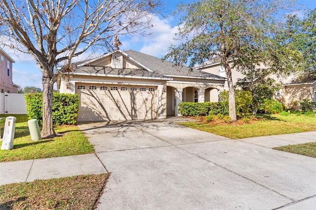 view of front of property with stucco siding, an attached garage, a front yard, fence, and driveway