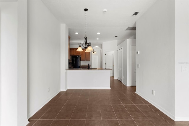 kitchen featuring a peninsula, dark tile patterned floors, visible vents, hanging light fixtures, and black refrigerator with ice dispenser