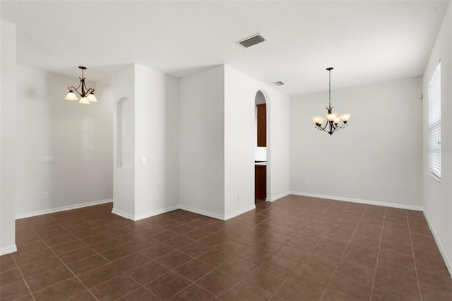 unfurnished room featuring baseboards, visible vents, and a notable chandelier