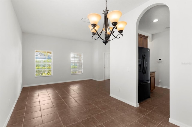 empty room featuring a chandelier, arched walkways, recessed lighting, dark tile patterned floors, and baseboards