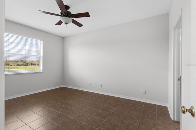 spare room featuring a ceiling fan, dark tile patterned flooring, and baseboards