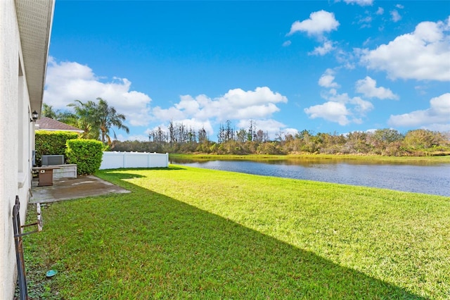 view of yard featuring a water view, fence, and central AC