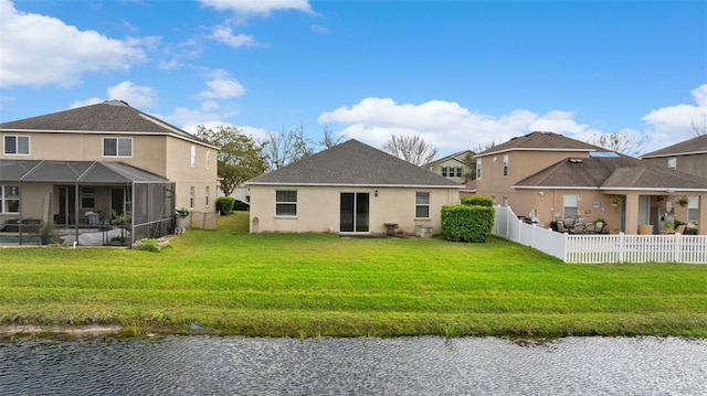 rear view of property with a lawn, a water view, a lanai, and fence