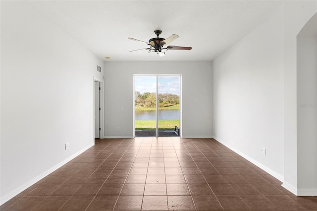 spare room featuring dark tile patterned floors, ceiling fan, visible vents, and baseboards