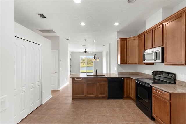 kitchen with a peninsula, black appliances, a sink, and decorative light fixtures