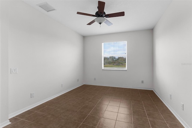 unfurnished room with dark tile patterned floors, visible vents, ceiling fan, and baseboards