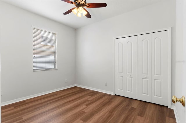 unfurnished bedroom featuring dark wood-type flooring, a closet, baseboards, and a ceiling fan