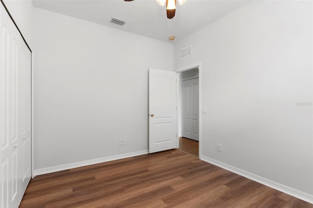 unfurnished bedroom featuring a closet, dark wood-style flooring, visible vents, and baseboards