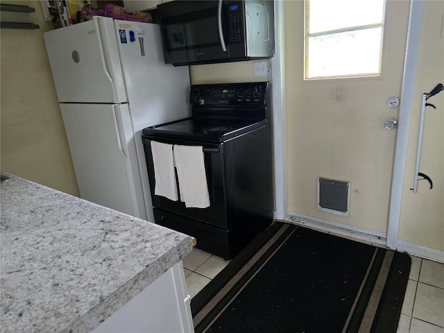 kitchen featuring electric range, white fridge, and light tile patterned flooring