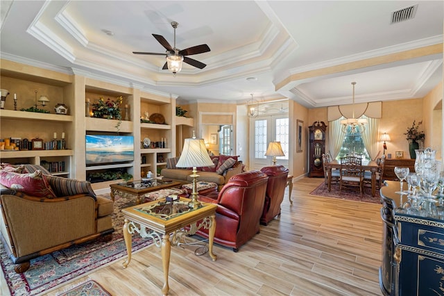 living room featuring crown molding, ceiling fan with notable chandelier, light wood-type flooring, and a raised ceiling